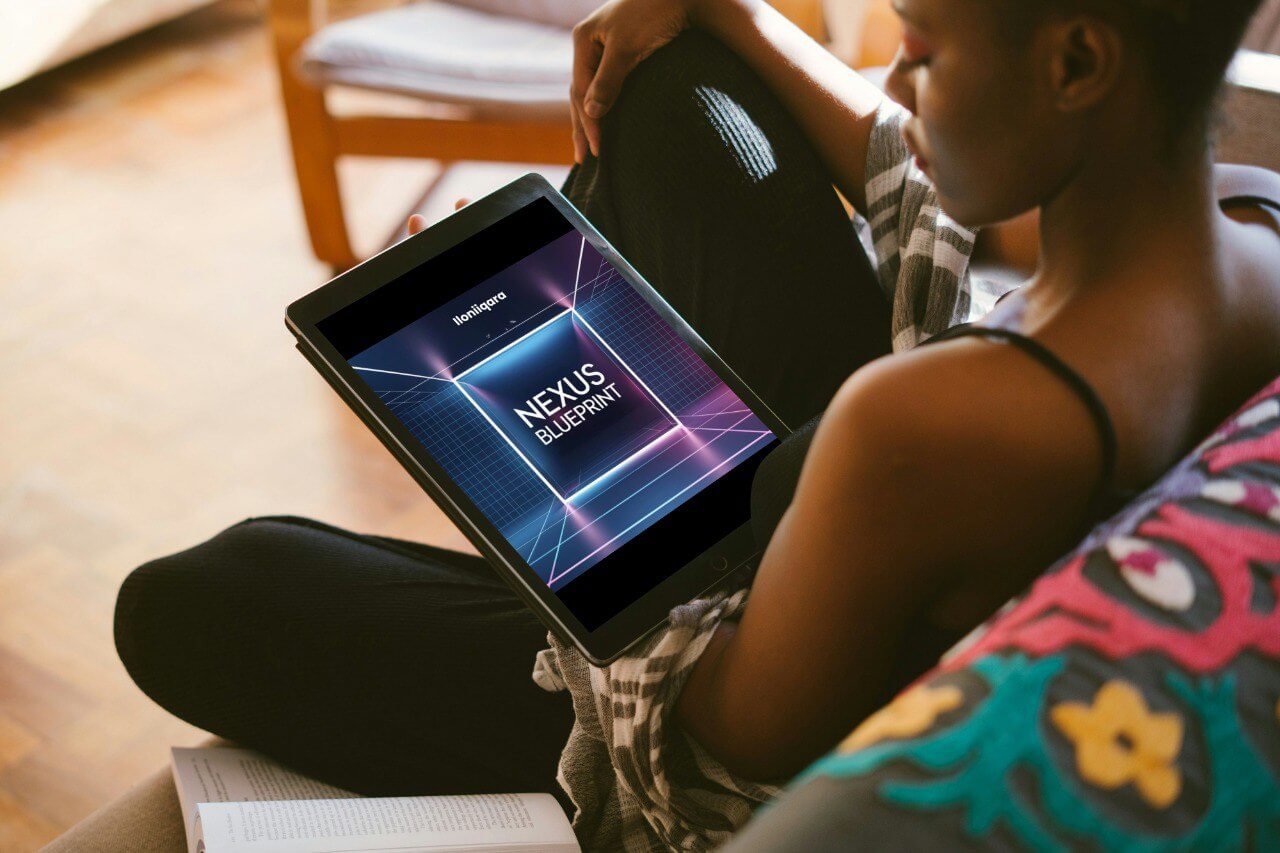 Person holding a tablet with 'Nexus Blueprint' guide displayed on the screen, sitting on a couch.