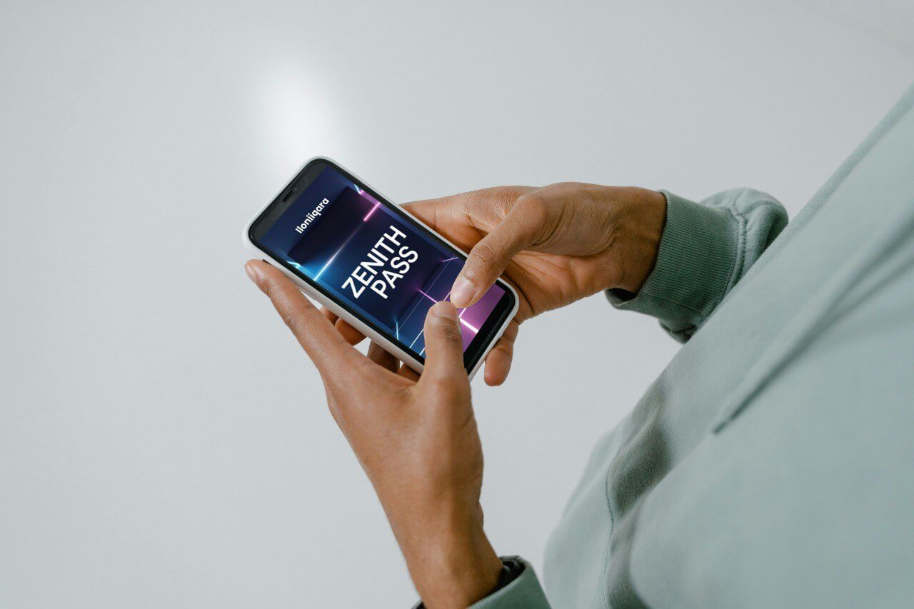 Person holding a smartphone with a visible screen displaying 'ZENITH PASS' guide on a plain background